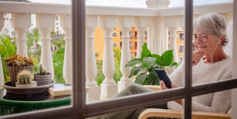 Senior Woman Using Phone on Balcony at an Independent Living Facility